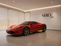 The glossy red Ferrari F8 Spider with yellow racing stripes is showcased in a modern showroom in Zurich.