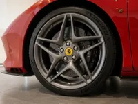 Ferrari F8 Spider's gloss red body and grey multi-spoke front wheel with yellow emblem are visible in Zurich.