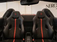 Ferrari F8 Spider's luxurious black leather sports seats with red racing stripes and embroidered logos, viewed from the interior in Zurich.