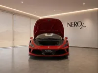 The red Ferrari F8 Spider is shown from the front with its frunk open, parked in a modern showroom in Zurich.