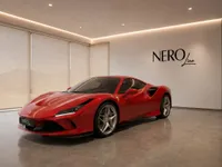 The striking red Ferrari F8 Tributo is showcased from a front three-quarter angle in a modern NEROline showroom in Lausanne.