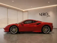 The red 2022 Ferrari F8 Tributo is showcased in a showroom, viewed from its side profile in Lausanne.