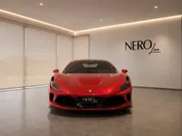 The striking gloss Rosso Corsa red 2022 Ferrari F8 Tributo supercar is showcased from a front view in a modern showroom in Lausanne.
