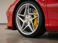 Close-up of the red Ferrari F8 Tributo's front wheel, featuring a silver multi-spoke rim and a prominent yellow brake caliper in Lausanne.