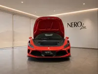 The front view of a red Ferrari F8 Tributo with its hood open, revealing the frunk, displayed in a showroom in Lausanne.