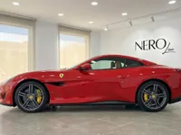 The red Ferrari Portofino convertible is showcased in a showroom in Madrid, displaying its sleek side profile and elegant design.