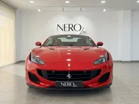 A gloss red 2019 Ferrari Portofino convertible is presented in a front view inside a showroom in Madrid.