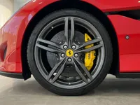 The red Ferrari Portofino displays its dark grey multi-spoke front wheel with bright yellow brake calipers in Madrid.