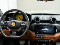 The Ferrari Portofino's luxurious cockpit in Madrid features a carbon fiber steering wheel, a prominent yellow tachometer, and a brown leather dashboard.