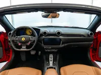 The luxurious interior of the Ferrari Portofino in Madrid, featuring a black dashboard, tan leather seats, and a prominent steering wheel with a yellow tachometer.