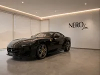 The black Ferrari Portofino is parked indoors in a modern showroom with the NERO line logo on the wall in Zurich.
