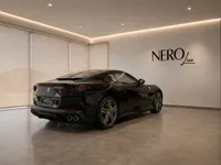 The black Ferrari Portofino is parked indoors, showing its elegant rear three-quarter view in Zurich.
