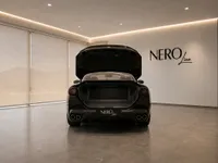 The black Ferrari Portofino is shown from the rear with its trunk open, parked in a modern NEROline showroom in Zurich.