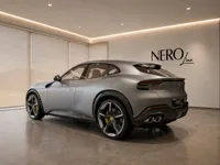 The 2023 Ferrari Purosangue in satin silver-grey, showcasing its sleek rear three-quarter view indoors in Lausanne.