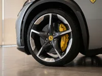 The Ferrari Purosangue in Satin Silver-Grey showcases its distinctive front wheel with two-tone rims and bright yellow brake calipers in Lausanne.