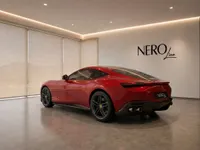 The stunning red Ferrari Roma is showcased from a rear three-quarter angle in a modern NEROline showroom in Lausanne.