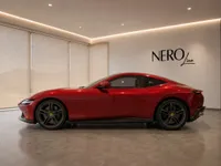 The sleek red Ferrari Roma is showcased in a modern showroom, highlighting its elegant side profile in Lausanne.