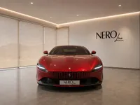 Front view of the glossy red 2022 Ferrari Roma parked in a modern showroom in Lausanne, featuring the NEROline logo.