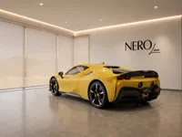 The yellow Ferrari SF90 Spider is showcased from a rear three-quarter view in a modern Zurich showroom.