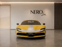 The yellow Ferrari SF90 with a silver stripe is presented in a modern showroom in Zurich, front view.