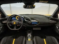 The luxurious cockpit of the 2022 Ferrari SF90 Spider in Zurich, featuring a black dashboard with yellow stitching and a sporty steering wheel.