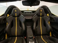 The luxurious interior of the Ferrari SF90 Spider in Zurich features black racing seats with vibrant yellow accents and stitching.