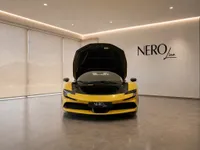 The yellow Ferrari SF90 Spider is showcased front-on in a Zurich showroom, with its front hood open.