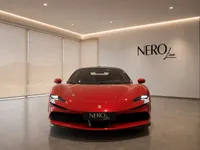 The striking Gloss Rosso Corsa Red 2021 Ferrari SF90 Stradale is prominently displayed in a modern showroom in Lausanne, viewed from the front.