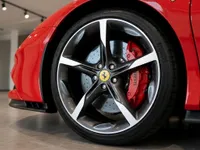 The front wheel of a red Ferrari SF90 Stradale in Lausanne, showcasing the multi-spoke rim and red brake caliper.