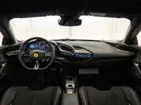 The luxurious interior of the Ferrari SF90 Stradale in Lausanne, showcasing its advanced digital cockpit, multifunction steering wheel, and black leather seats.