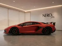 Matte red Lamborghini Aventador SVJ supercar displayed in a modern showroom with the NEROline logo in Lausanne.