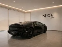 The sleek black Lamborghini Huracán Coupé is showcased from a rear three-quarter view in a modern NEROline showroom in Zurich.