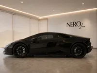 The sleek gloss black Lamborghini Huracán Coupé is showcased in a modern showroom in Zurich, viewed from its side profile.