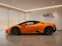 A matte orange Lamborghini Huracán EVO Spyder is parked indoors, showcasing its sleek side profile in Zurich.