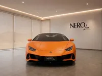 A matte orange Lamborghini Huracán EVO Spyder is parked head-on in a modern showroom with a 'NEROline' logo in Zurich.
