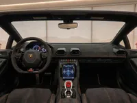 The luxurious interior of the Lamborghini Huracán EVO Spyder in Zurich, showing its dashboard, steering wheel, and black seats with orange stitching.