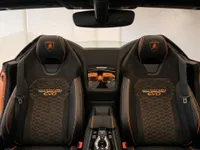 The luxurious black and orange interior seats of the Lamborghini Huracán EVO Spyder, revealing the engine bay between them in Zurich.