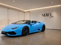 A bright blue Lamborghini Huracán Spyder is parked indoors, showcasing its sleek design from a front three-quarter angle in Zurich.