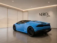 A gloss bright blue Lamborghini Huracán Spyder is parked indoors, shown from a rear three-quarter angle in Zurich.