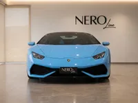 A light blue Lamborghini Huracán Spyder is parked head-on in a showroom with the NERO line logo on the wall in Zurich.