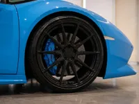 The front wheel of a blue Lamborghini Huracán Spyder in Zurich, showcasing its black multi-spoke rim and blue brake caliper.