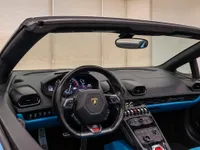 The interior of a Lamborghini Huracán Spyder in Zurich, featuring its steering wheel, dashboard, and center console with blue accents.