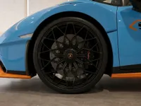 Close-up of the black multi-spoke wheel, brake caliper, and gloss Blu Laufey light blue front fender of the Lamborghini Huracán STO.