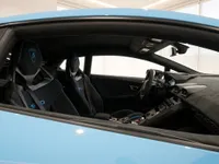 The interior of the Lamborghini Huracán STO in Lausanne, showing black bucket seats with blue stitching and a detailed dashboard.