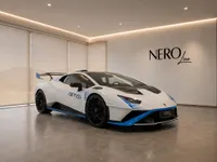 White Lamborghini Huracán STO with blue accents, parked in a modern showroom with the NEROline logo in Zurich.