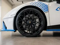 The white Lamborghini Huracán STO showcases its black multi-spoke front wheel with blue accents, parked in Zurich.