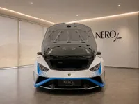 The white Lamborghini Huracán STO is shown from the front with its frunk open in a modern showroom in Zurich.