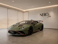 A striking green Lamborghini Huracán STO is showcased in a modern, well-lit showroom in Zurich, presented from a front three-quarter angle.