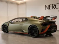 The green Lamborghini Huracán STO is showcased from a rear three-quarter angle in a modern showroom in Zurich.