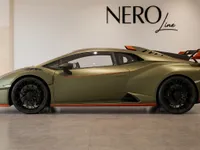A green Lamborghini Huracán STO is parked in a showroom, showcasing its sleek side profile and orange accents in Zurich.